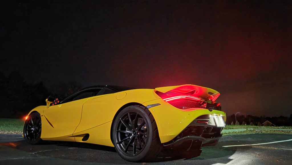 Yellow McLaren 720S Spider rear three-quarter view at night with raised rear spoiler